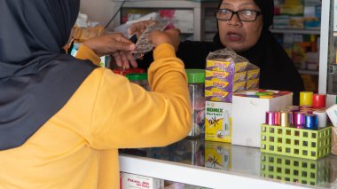 Pinrang Endonezya 30 Eylül 2023: Endonezya, Endonezya 'da sabah saatlerinde bir eczaneden tablet ilaç alan Asyalı bir kadının portresi 