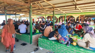 pinrang Endonezya, Ocak 05 2024: Birkaç kişi bir off-shore restoranının çatısı altında toplandı. Plaj ve aşçılık turizmi, Ammani Pinrang Sahili, Endonezya