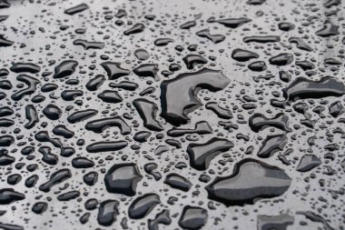 Soyut arkaplan, siyah bir arabanın kaputundaki yağmur damlaları, doku yağmur damlaları Asya Endonezya