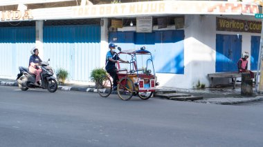 Pinrang Endonezya, 12 Haziran 2024: Orta yaşlı bir adamın portresi, sabahleyin Pinrang City, Asya Endonezya sokaklarında üç tekerlekli bir araçla geziyor.