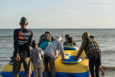 Pinrang Endonezya, 14 Ağustos 2024: Birkaç yerli Endonezyalı turist, öğleden sonra Güney Sulawesi, Asya Endonezya 'da, Pinrang plajında kauçuk bir tekneye binmenin heyecanını yaşıyor.