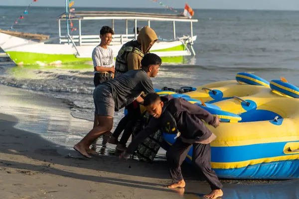 Pinrang Endonezya, 14 Ağustos 2024: Birkaç yerli Endonezyalı turist, öğleden sonra Güney Sulawesi, Asya Endonezya 'da, Pinrang plajında kauçuk bir tekneye binmenin heyecanını yaşıyor.