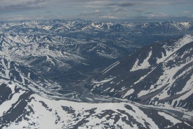 Rusya 'nın Magadan bölgesindeki karla kaplı dağların havadan görünüşü. Dağların kış manzarası. Rusya 'nın en kuzeyine giden bir uçak. Sibirya ve Rusya 'nın doğası Uzak Doğu.