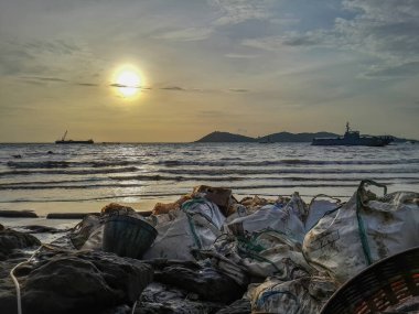 Tayland Körfezi ve Samet Adaları 'nın ortasında, Rayong Denizi' nin ortasındaki ham petrol sızıntısı. Personel ve gönüllüler kumsaldaki petrol sızıntılarını temizlemeye yardım ediyor, yağmur yağıyor.