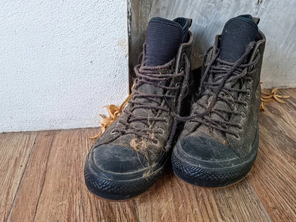 Black leather shoes, boots or ankle boots that are covered with dust, leaves and cat hair, look dirty and very old.