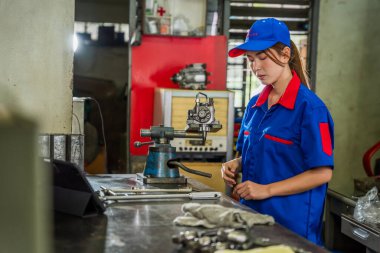 Garajda mavi üniformalı kadın bir dizel motor tamircisi çalışıyor. Yakıt basıncı yükseltici pompa sistemini ve ortak demiryolu enjektörlerini inceleyin ve muhafaza edin.