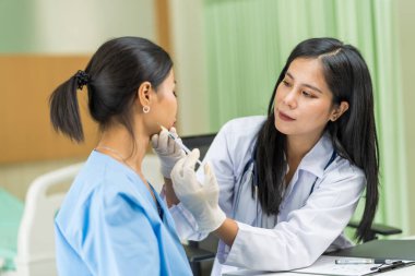 Asyalı kadın estetik cerraha danışmanlık yapıyor ve güzellik işlemleri için yüzüne botoks yaptırıyor. Bir kadının yüzünde estetik ameliyat