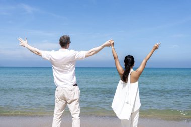 Farklı milletlerden iki erkek ve kadın kumsala birlikte mutlu bir şekilde yürüyorlar. yaz tatilinde