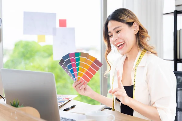 stock image Asian female clothing designers Thailand communicating with customers through laptops in their home office. Showing various color patterns for customers to choose from cut dress as the customer wants.