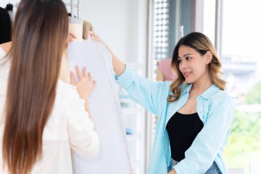 Küçük işletmeler, KOBİ 'de birlikte çalışan iki Asyalı kadın müşteriler için terzilik tasarımı yapıyor. İkisi de büyük tasarımcılar gibi davrandılar..