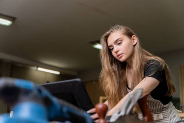 Bir kadın marangozun portresi bir mobilya fabrikasında mobilyalarını yaptığı için tablet üzerindeki tasarımlara bakıyor. bir çok alet ve ahşap ile