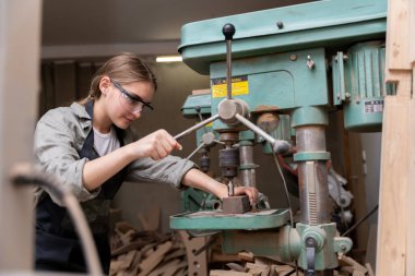 Mobilya fabrikasında mobilya yapmak için alet kullanan bir kadın marangozun portresi. modern araçlarla