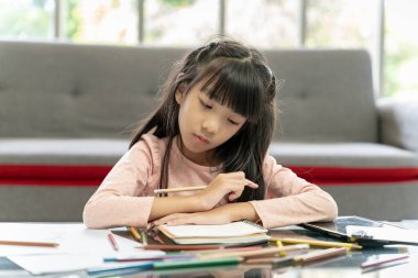 Asyalı kız ödevini evde yapıyor.