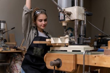 Bir kadın marangozun portresi, mobilya fabrikasında mobilya yapmak için aletler ya da makineler kullanıyor, matkap değil. modern araçlarla