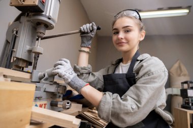 Bir kadın marangozun portresi, mobilya fabrikasında mobilya yapmak için aletler ya da makineler kullanıyor, matkap değil. modern araçlarla