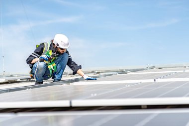 Male engineer installing or checking the working condition of solar panels on the roof or at the height of the factory for saving electricity was broken to use renewable energy from the sun