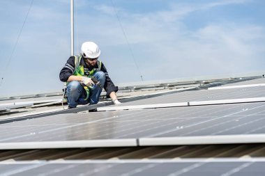 Male engineer installing or checking the working condition of solar panels on the roof or at the height of the factory for saving electricity was broken to use renewable energy from the sun