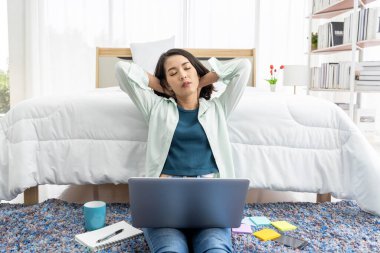 Asian woman working at bedside in bedroom at home with her tablet