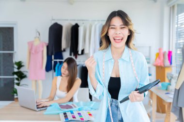 Küçük işletmeler, KOBİ 'de birlikte çalışan iki Asyalı kadın müşteriler için terzilik tasarımı yapıyor. İkisi de büyük tasarımcılar gibi davrandılar..