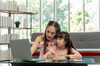 Asyalı aile portresi, baba ve kız oturma odasında. Kız, ev ödevini annesiyle yapmış, tavsiye vermiş ve yakından öğretmiş..