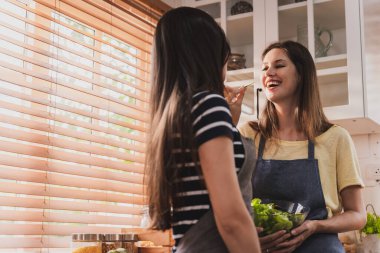 Female and female or LGBT couples are happily cooking bread together in the home kitchen.
