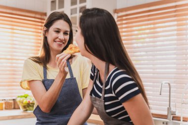 Female and female or LGBT couples are happily cooking bread together in the home kitchen.