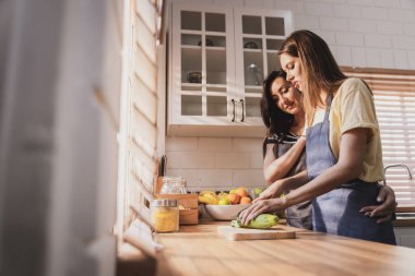 Female and female or LGBT couples are happily cooking bread together in the home kitchen.
