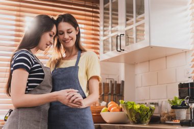Female and female or LGBT couples are happily cooking bread together in the home kitchen.