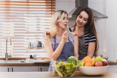 Female and female or LGBT couples are happily cooking bread together in the home kitchen.