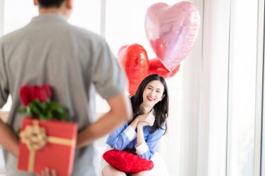Asian couple Showing love surprise giving flowers or gifts to each other on important occasions such Valentine's Day birthdays or wedding anniversaries with love and warmth in bedroom of their home