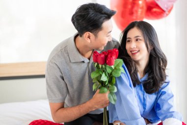 Asian couple Showing love surprise giving flowers or gifts to each other on important occasions such Valentine's Day birthdays or wedding anniversaries with love and warmth in bedroom of their home