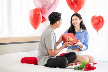 Asian couple Showing love surprise giving flowers or gifts to each other on important occasions such Valentine's Day birthdays or wedding anniversaries with love and warmth in bedroom of their home