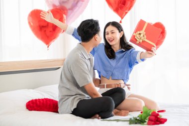 Asian couple Showing love surprise giving flowers or gifts to each other on important occasions such Valentine's Day birthdays or wedding anniversaries with love and warmth in bedroom of their home