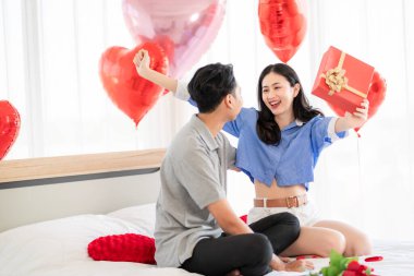 Asian couple Showing love surprise giving flowers or gifts to each other on important occasions such Valentine's Day birthdays or wedding anniversaries with love and warmth in bedroom of their home