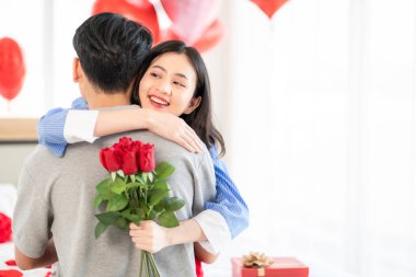 Asian couple Showing love surprise giving flowers or gifts to each other on important occasions such Valentine's Day birthdays or wedding anniversaries with love and warmth in bedroom of their home