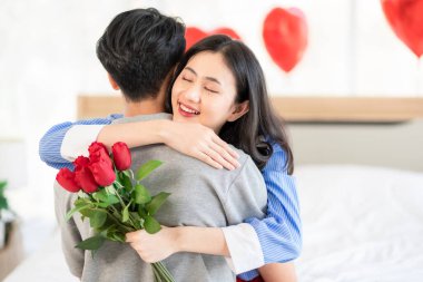 Asian couple Showing love surprise giving flowers or gifts to each other on important occasions such Valentine's Day birthdays or wedding anniversaries with love and warmth in bedroom of their home