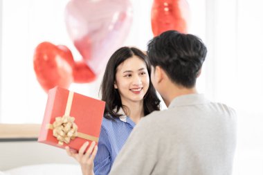 Asian couple Showing love surprise giving flowers or gifts to each other on important occasions such Valentine's Day birthdays or wedding anniversaries with love and warmth in bedroom of their home