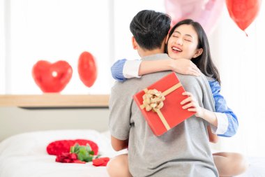 Asian couple Showing love surprise giving flowers or gifts to each other on important occasions such Valentine's Day birthdays or wedding anniversaries with love and warmth in bedroom of their home