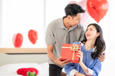 Asian couple Showing love surprise giving flowers or gifts to each other on important occasions such Valentine's Day birthdays or wedding anniversaries with love and warmth in bedroom of their home