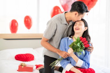 Asian couple Showing love surprise giving flowers or gifts to each other on important occasions such Valentine's Day birthdays or wedding anniversaries with love and warmth in bedroom of their home
