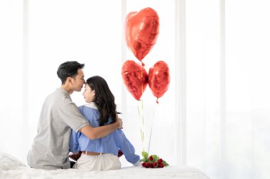 Asian couple Showing love surprise giving flowers or gifts to each other on important occasions such Valentine's Day birthdays or wedding anniversaries with love and warmth in bedroom of their home