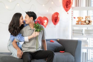 Asian couple Showing love surprise giving flowers or gifts to each other on important occasions such Valentine's Day birthdays or wedding anniversaries with love and warmth in bedroom of their home