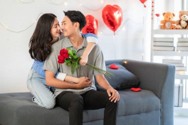Asian couple Showing love surprise giving flowers or gifts to each other on important occasions such Valentine's Day birthdays or wedding anniversaries with love and warmth in bedroom of their home