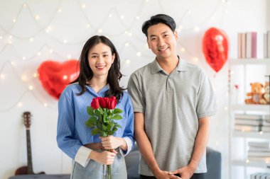 Asian couple Showing love surprise giving flowers or gifts to each other on important occasions such Valentine's Day birthdays or wedding anniversaries with love and warmth in bedroom of their home