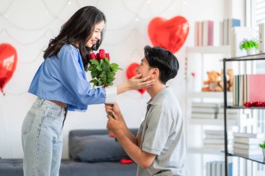 Asian couple Showing love surprise giving flowers or gifts to each other on important occasions such Valentine's Day birthdays or wedding anniversaries with love and warmth in bedroom of their home