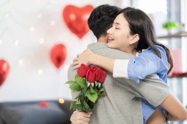 Asian couple Showing love surprise giving flowers or gifts to each other on important occasions such Valentine's Day birthdays or wedding anniversaries with love and warmth in bedroom of their home
