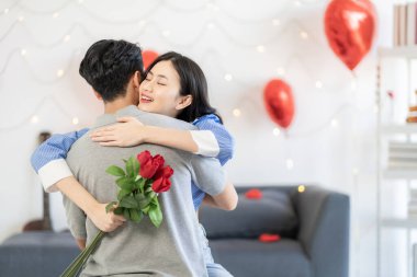 Asian couple Showing love surprise giving flowers or gifts to each other on important occasions such Valentine's Day birthdays or wedding anniversaries with love and warmth in bedroom of their home
