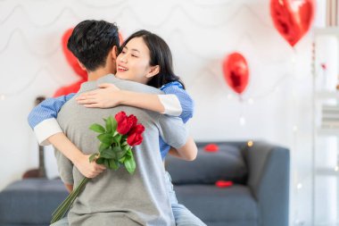 Asian couple Showing love surprise giving flowers or gifts to each other on important occasions such Valentine's Day birthdays or wedding anniversaries with love and warmth in bedroom of their home