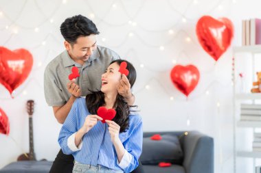 Asian couple Showing love surprise giving flowers or gifts to each other on important occasions such Valentine's Day birthdays or wedding anniversaries with love and warmth in bedroom of their home