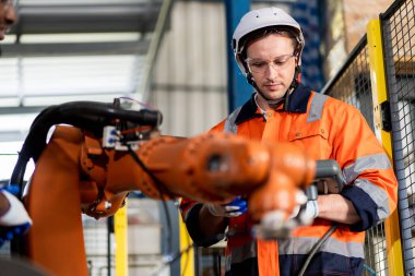 Erkek ve kadın mühendislerden oluşan bir ekip bilgisayar kontrollü çelik kaynaklama robotlarını incelemek için toplanıyor. Provalar ve kullanım için kurulum planı.